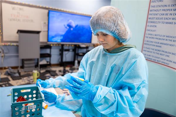 student in scrubs working at tables